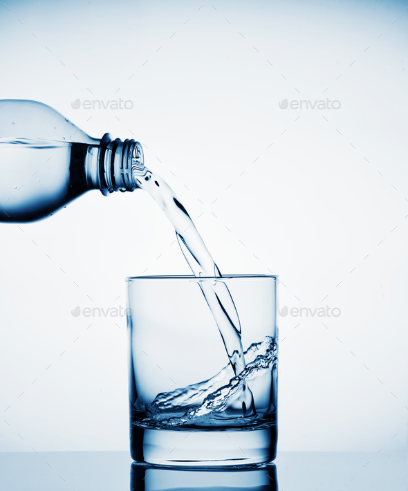 Water pouring into a wide glass from a bottle Stock Photo by Alexlukin